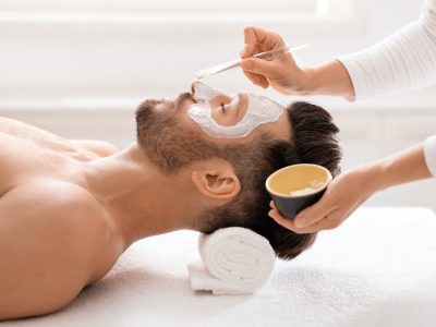 Bearded man getting face treatment at spa salon